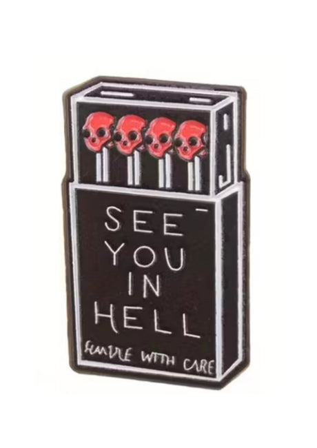 Schwarze Emaille-Anstecknadel in Form einer Streichholzschachtel mit rotem Totenkopf und Streichhölzern.