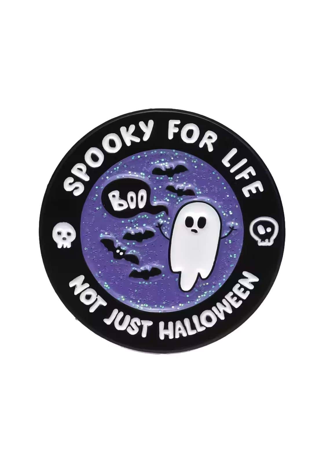 Runde schwarze Emaille-Anstecknadel mit lilafarbenem Glitzerhintergrund, auf dem ein Geist, Fledermäuse und Totenköpfe abgebildet sind.