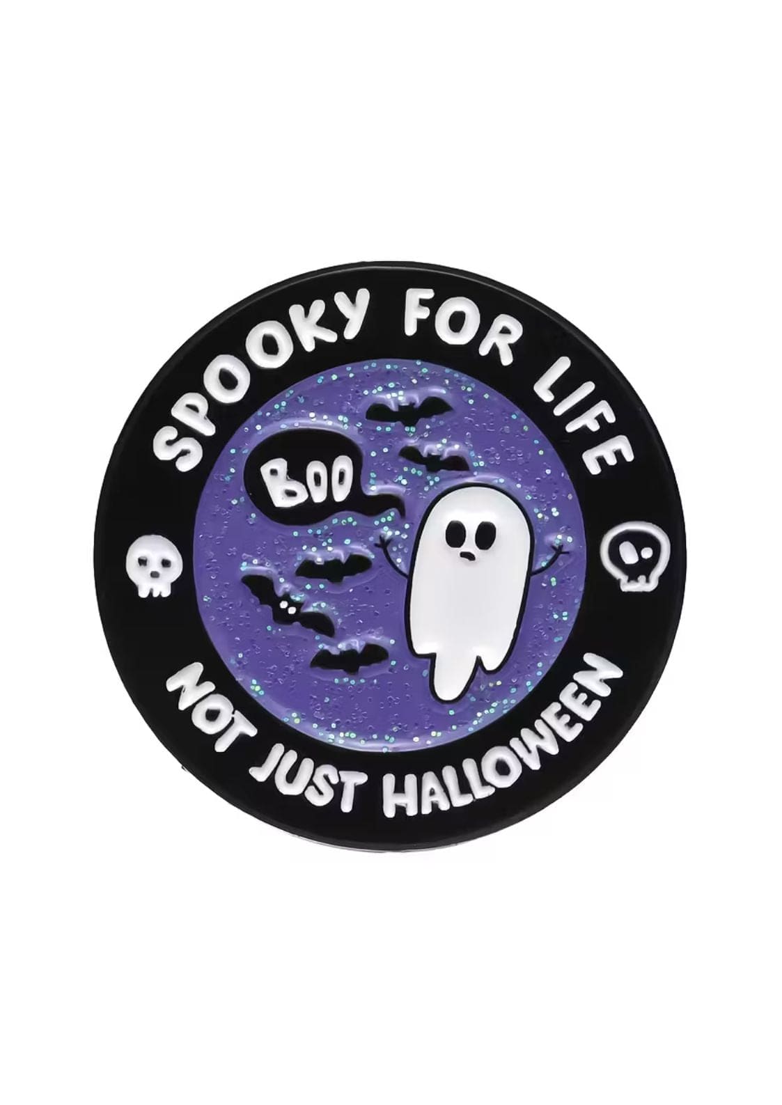 Runde schwarze Emaille-Anstecknadel mit lilafarbenem Glitzerhintergrund, auf dem ein Geist, Fledermäuse und Totenköpfe abgebildet sind.