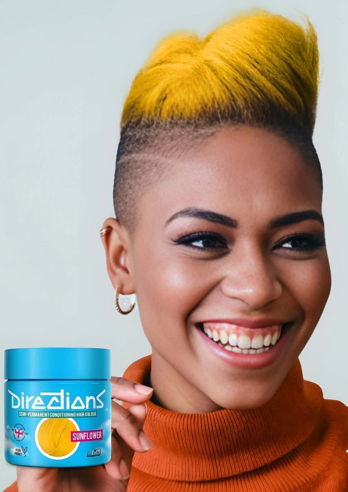 Eine lächelnde frau hält einen leuchtend blauen direzions jar mit intensiv leuchtender gelber haarfarbe sonnenblumenrichtungen 100ml