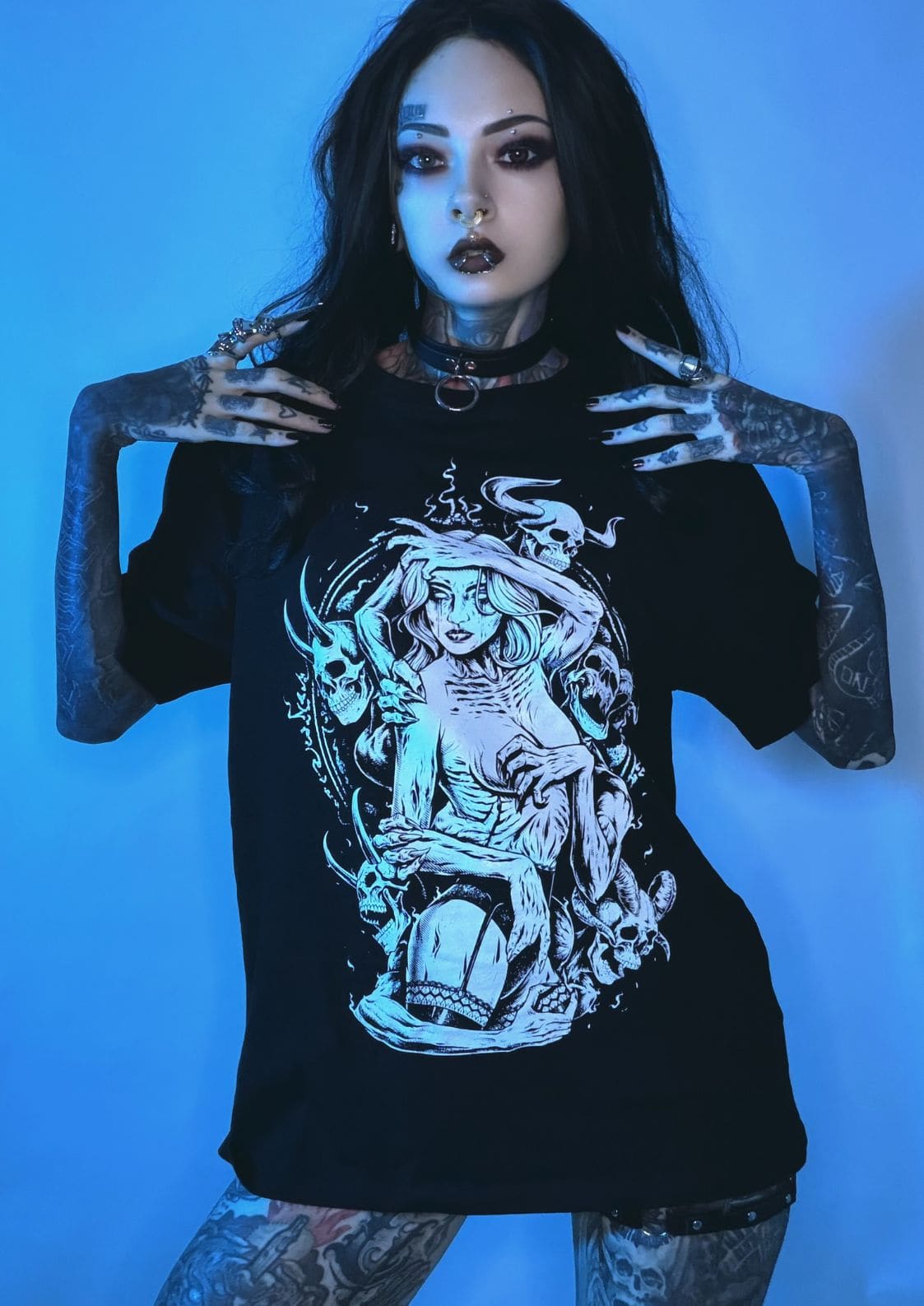 Schwarzes Grafik-T-Shirt mit detaillierter weißer Illustration einer gotikstiligen Frau, umgeben von Schädeln und dämonischen Elementen.