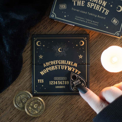 Travel ouija board schwarz und gold mit okkultem design und passendem planchette auf holzoberfläche neben verpackung